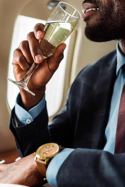 Vue recadrée d'un homme d'affaires afro-américain buvant du champagne en avion privé — Photo de stock