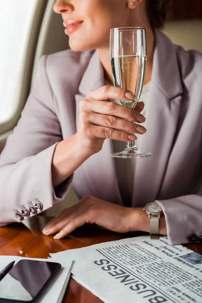 Cropped view of businesswoman holding champagne glass in private plane — Stock Photo