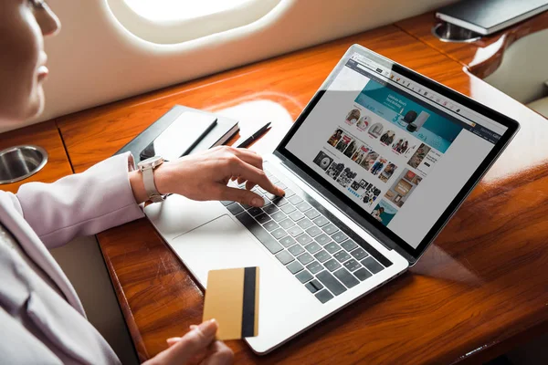 Cropped view of businesswoman using laptop with amazon website while shopping online in private plane — Stock Photo