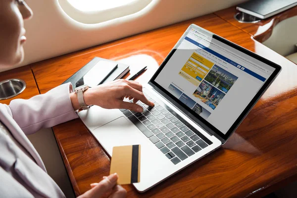 Vista recortada de la mujer de negocios utilizando el ordenador portátil con el sitio web de reserva, mientras que las compras en línea en avión privado - foto de stock
