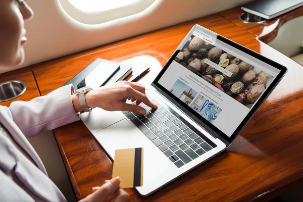 Vista cortada de empresária usando laptop com site depositphotos enquanto faz compras on-line em avião privado — Fotografia de Stock