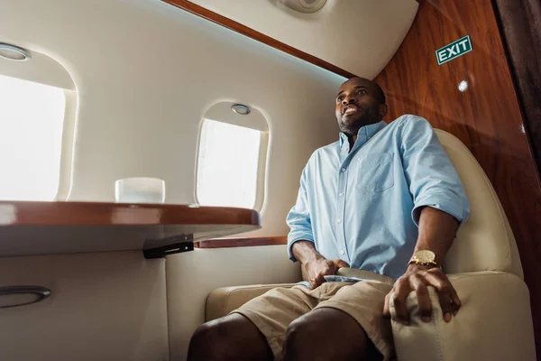 Terrified african american man flying in private jet — Stock Photo