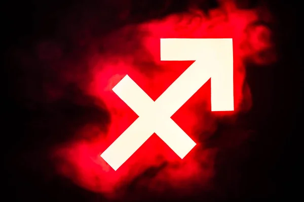 Signo zodiacal rojo iluminado de Sagitario con humo en el fondo - foto de stock