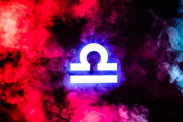 Signe du zodiaque Balance illuminé bleu avec fumée colorée rouge sur le fond — Photo de stock