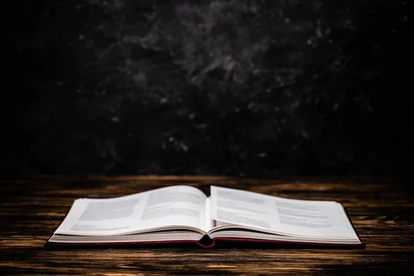 Open astrological book on wooden table on black background — Stock Photo