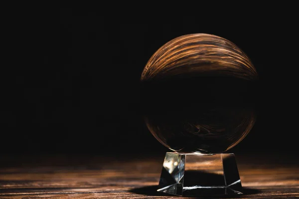 Boule de cristal sur table en bois sur fond noir — Photo de stock
