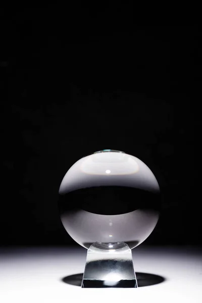 Bola de cristal sobre superficie blanca sobre fondo negro - foto de stock