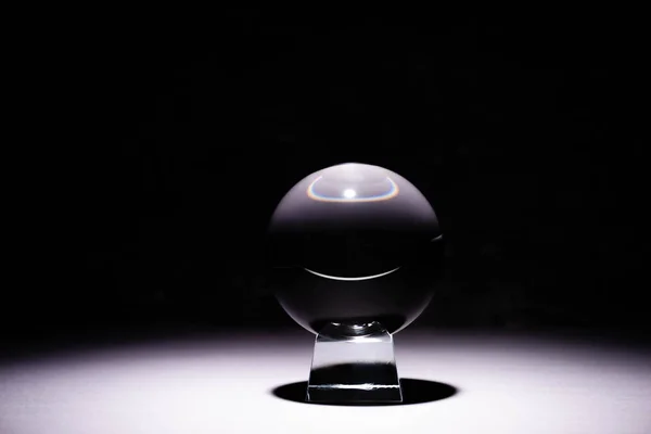 Crystal ball on white surface on black background — Stock Photo