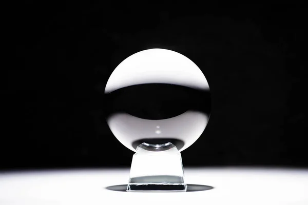 Crystal ball on white surface on black background — Stock Photo