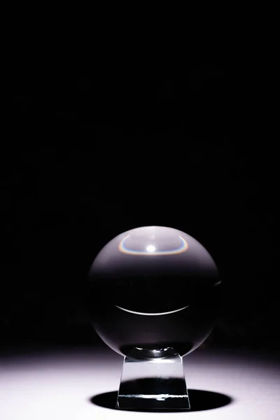 Crystal ball on white surface on black background — Stock Photo