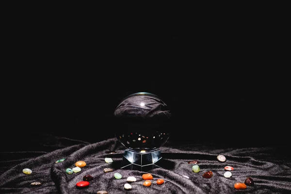 Crystal ball with fortune telling stones on black velvet cloth isolated on black — Stock Photo