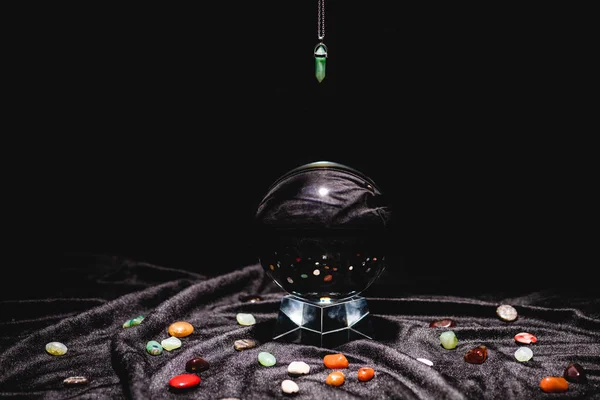 Fortune telling stone above crystal ball on black velvet cloth isolated on black — Stock Photo