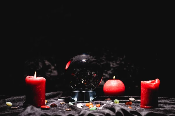 Crystal ball with fortune telling stones and candles on black velvet cloth — Stock Photo