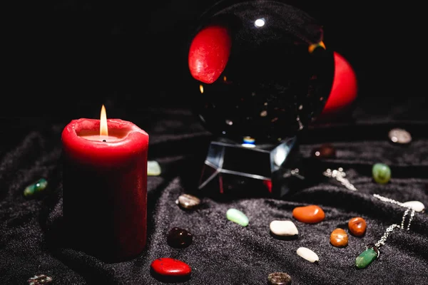 Selective focus of crystal ball with fortune telling stones and candle on black velvet cloth — Stock Photo