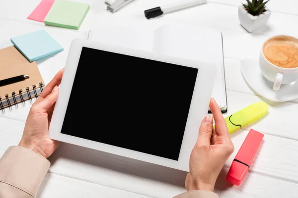 Abgeschnittene Ansicht einer Frau, die am Arbeitsplatz ein digitales Tablet mit Bürobedarf und Kaffee in der Hand hält — Stockfoto