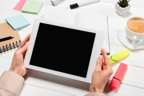 Vue recadrée de la femme tenant tablette numérique sur le lieu de travail avec fournitures de bureau et café — Photo de stock