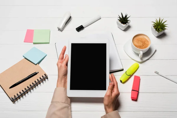 Partial view of woman holding digital tablet at workplace with office supplies and coffee — Stock Photo