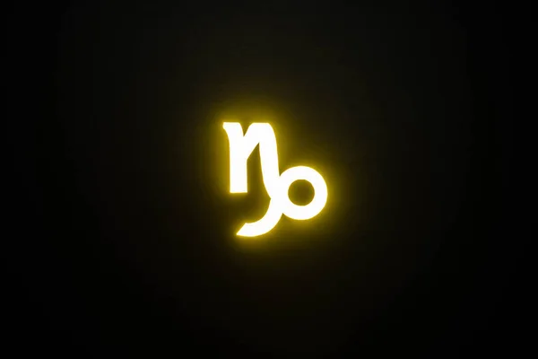 Signo del zodíaco Capricornio iluminado amarillo aislado en negro - foto de stock