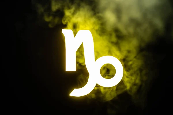 Yellow illuminated Capricorn zodiac sign with smoke on background — Stock Photo