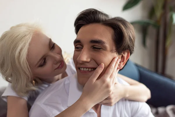 Smiling blonde girl touching boyfriend face at home — Stock Photo