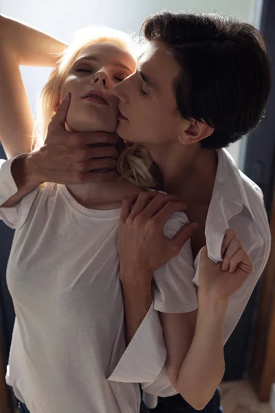 Joven hombre sosteniendo por el cuello mujer rubia en la luz del sol — Stock Photo