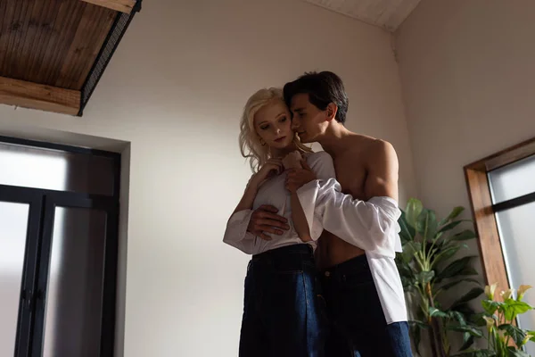 Homme torse nu embrassant belle fille blonde dans le salon — Photo de stock