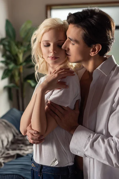 Hombre guapo abrazando a mujer joven en la sala de estar - foto de stock