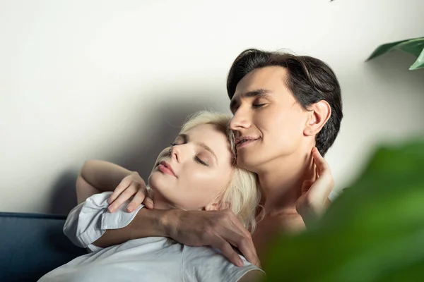 Vue latérale du couple souriant avec les yeux fermés embrassant à la maison — Photo de stock