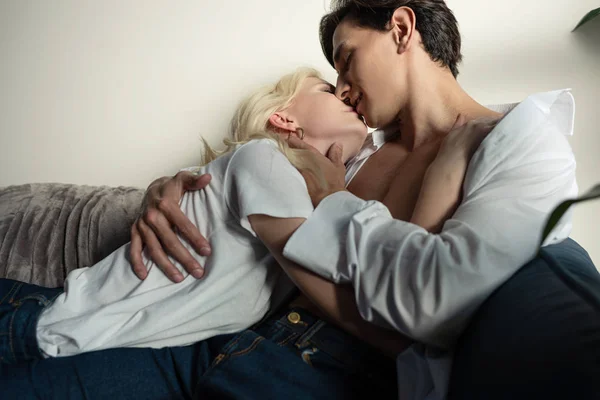 Young couple embracing and kissing on sofa in living room — Stock Photo