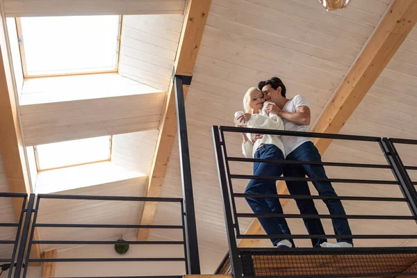 Blick auf ein junges Paar, das sich auf dem Balkon umarmt und eine Kaffeetasse in der Hand hält — Stockfoto