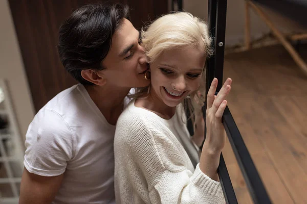 Schöner Mann flüstert seiner lächelnden Freundin zu Hause zu — Stockfoto