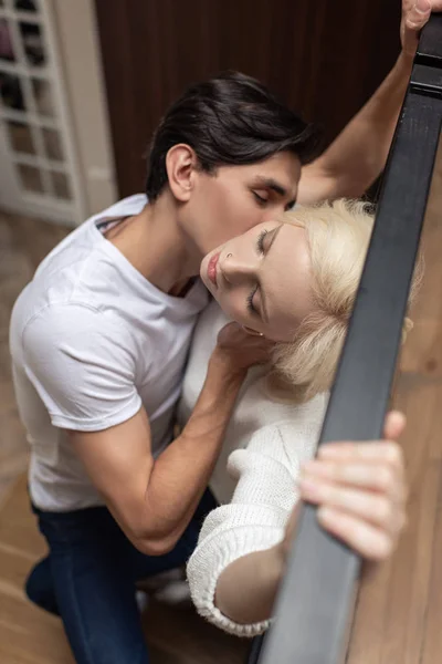 Selective focus of man kissing attractive girlfriend by balcony railing — Stock Photo