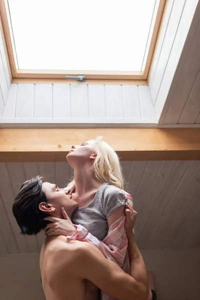 Bonito homem abraçando namorada sob janela do telhado — Fotografia de Stock