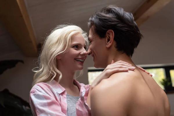 Mujer sonriente mirando a su novio sin camisa en casa - foto de stock
