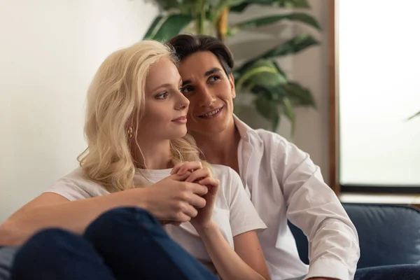 Smiling couple sitting on sofa in living room — Stock Photo