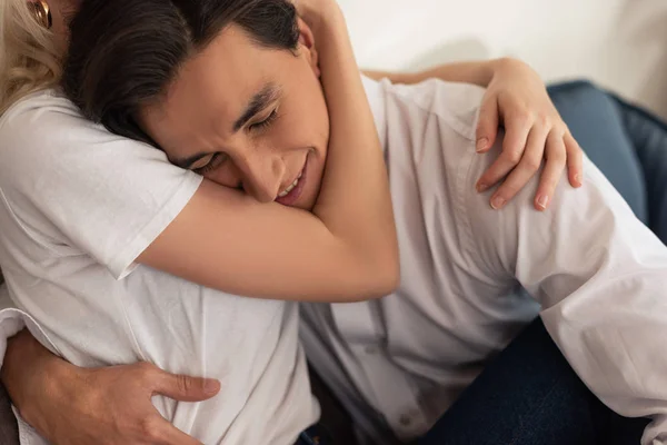 Sorrindo homem abraçando namorada no sofá na sala de estar — Fotografia de Stock