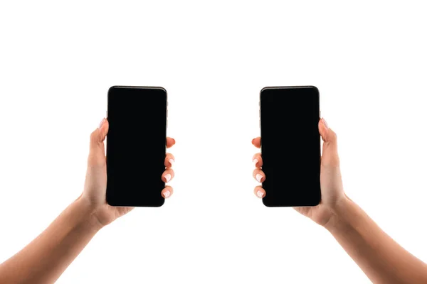 Vista recortada de la mujer sosteniendo teléfonos inteligentes aislados en blanco — Stock Photo