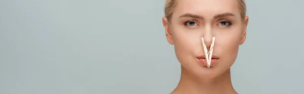 Panoramic shot of attractive woman with wooden pin on nose isolated on grey — Stock Photo