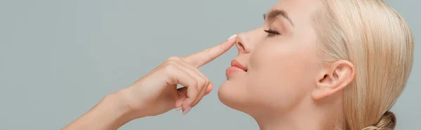 Panoramic shot of happy woman touching nose isolated on grey — Stock Photo