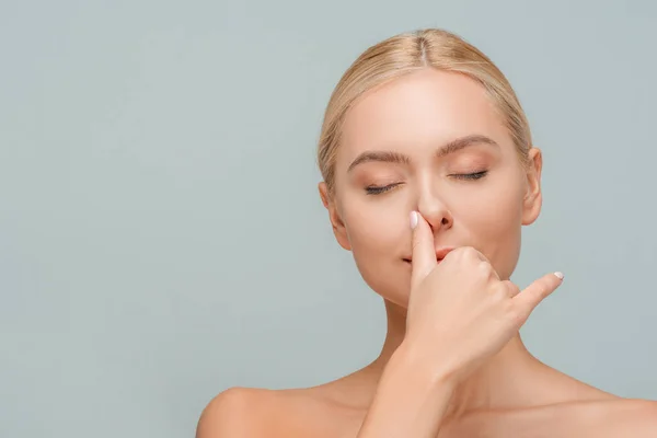 Attractive girl with closed eyes touching nose isolated on grey — Stock Photo