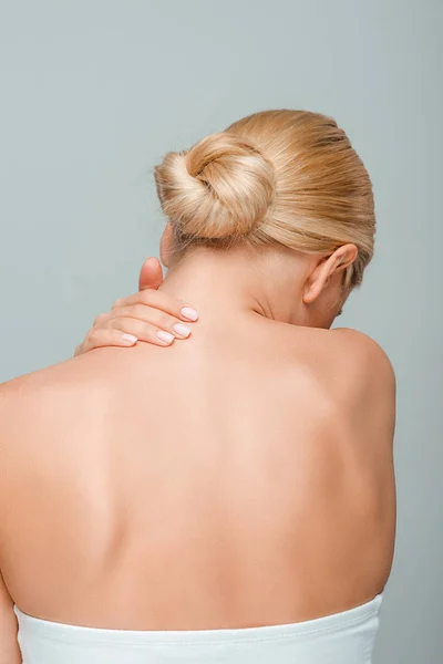Back view of girl touching neck isolated on grey — Stock Photo