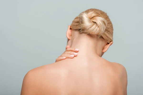 Вид ззаду гола жінка торкається шиї ізольовано на сірому — стокове фото