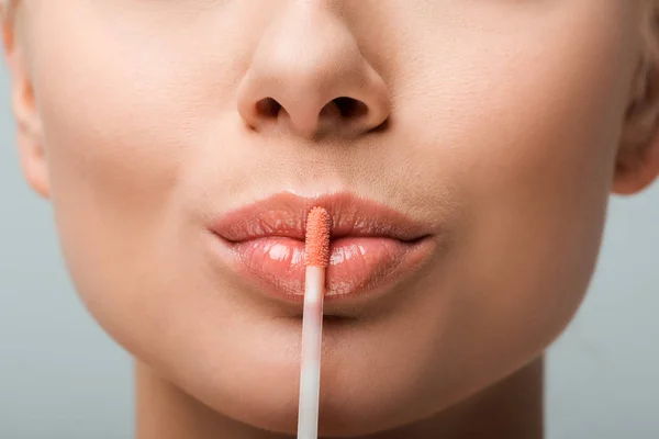 Nahaufnahme auf Lipgloss neben glänzenden Lippen von Frau isoliert auf grau — Stockfoto