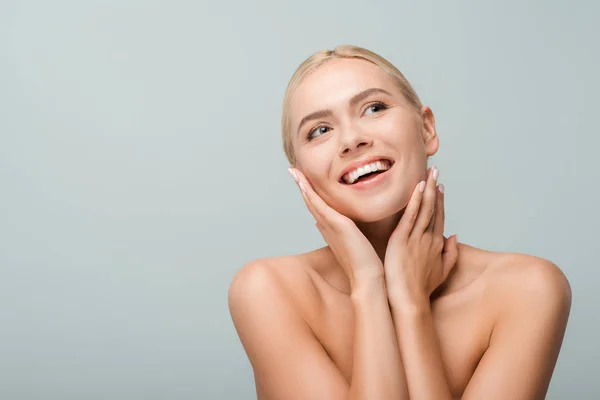 Cheerful girl touching neck and smiling isolated on grey — Stock Photo