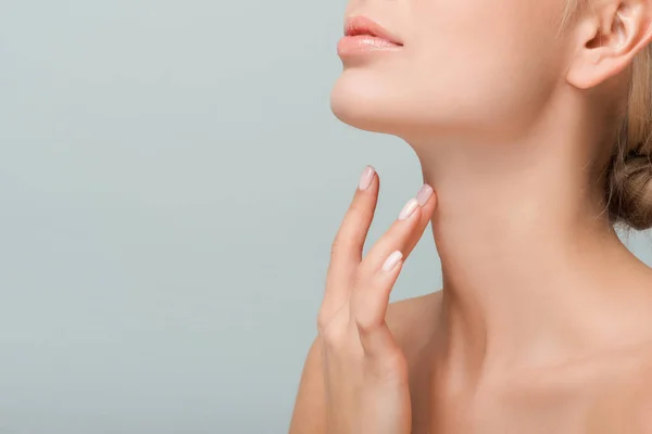 Vista recortada de la mujer tocando el cuello aislado en gris - foto de stock