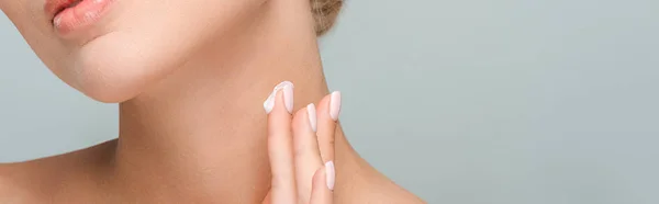 Panoramic shot of woman applying cosmetic cream on neck isolated on grey — Stock Photo