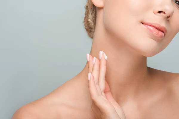 Cropped view of woman applying cosmetic cream on neck isolated on grey — Stock Photo