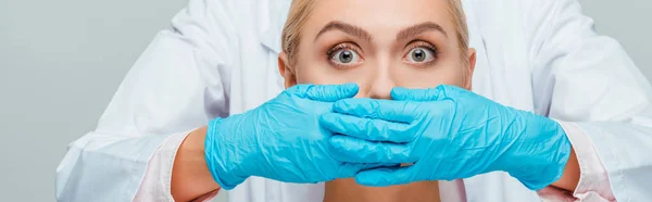 Panoramic shot of beautician covering mouth of woman isolated on grey — Stock Photo