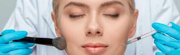 Tiro panorâmico de esteticista em luvas de látex segurando escova cosmética e seringa perto de menina com olhos fechados — Fotografia de Stock