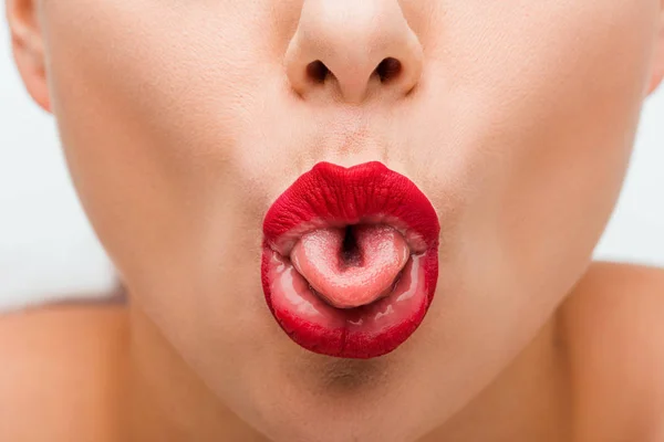 Vista recortada de mujer joven con labios rojos que sobresalen lengua aislada en blanco - foto de stock